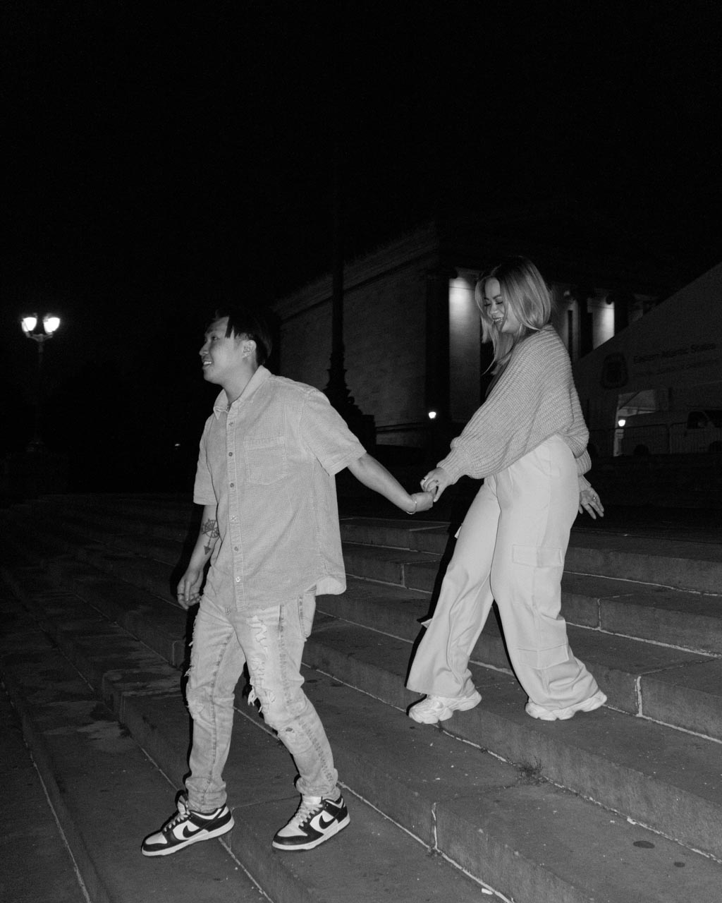 A black and white shot of a newly engaged couple walking down the museum steps